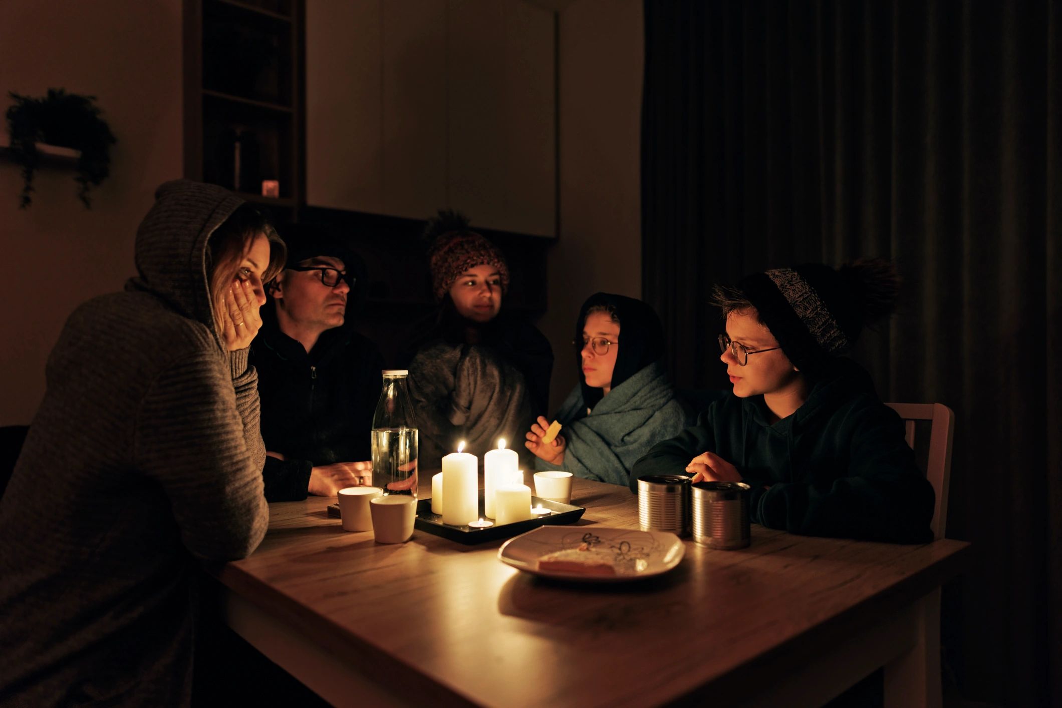Family gathered at a table by candlelight during a power outage