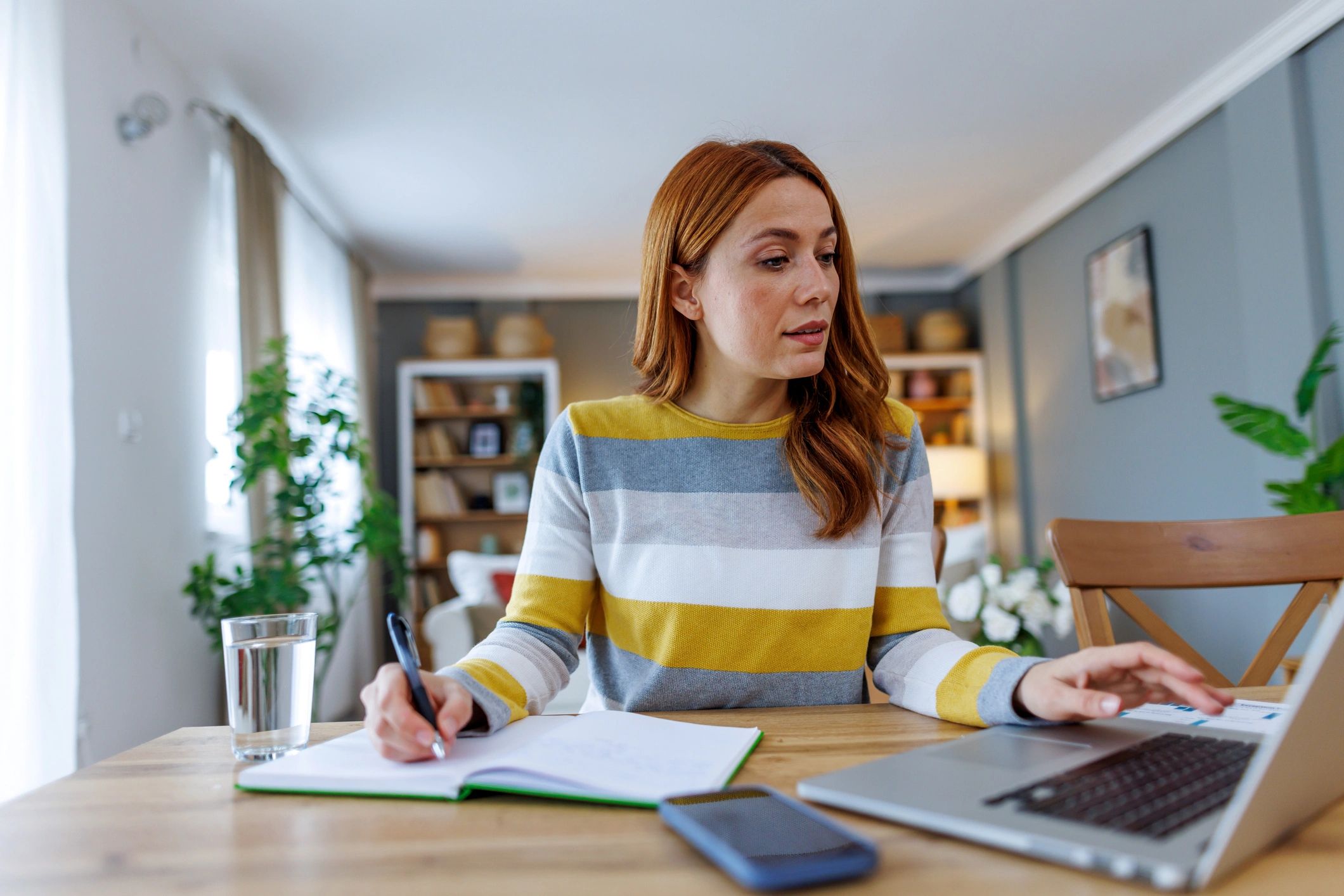 Person reviewing a checklist while working on a laptop at home